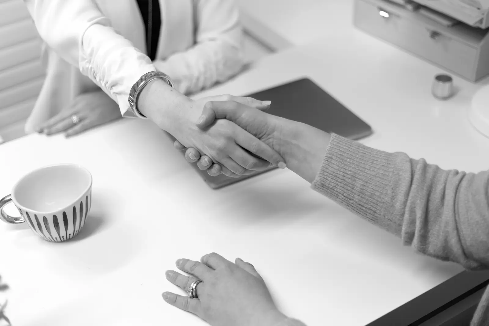 Deux personnes se serrent la main au-dessus d’une table