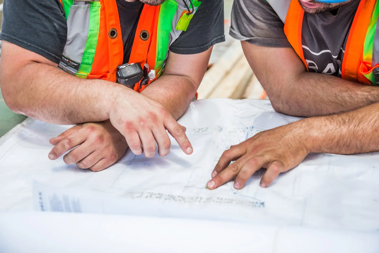 Deux compagnons en gilet relisent un plan sur une table