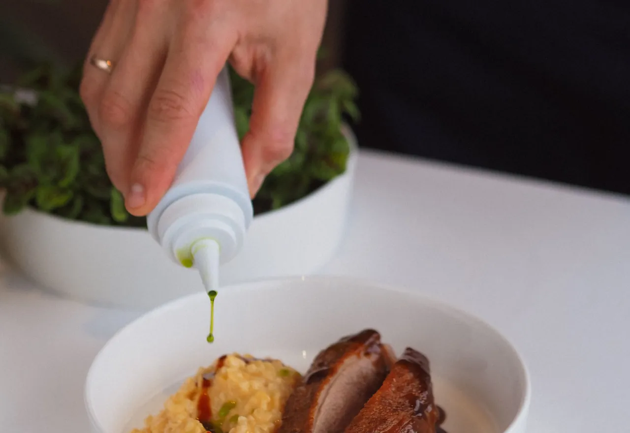 Les mains de la cheffe dressant une assiette